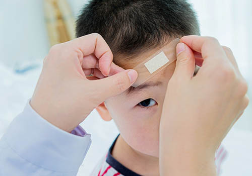 Young boy getting bandage placed on forehead